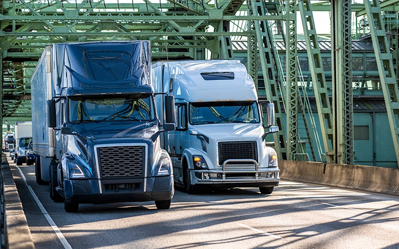 image of two trucks side-by-side driving on a bridge